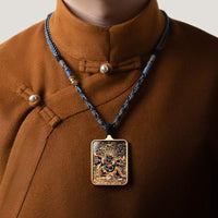 A person in a brown traditional outfit wears Joyce’s Tibetjewelry’s Thangka Pendant—a hand-painted Palden Lhamo amulet necklace for protection and prosperity, reflecting Tibetan spiritual artistry.